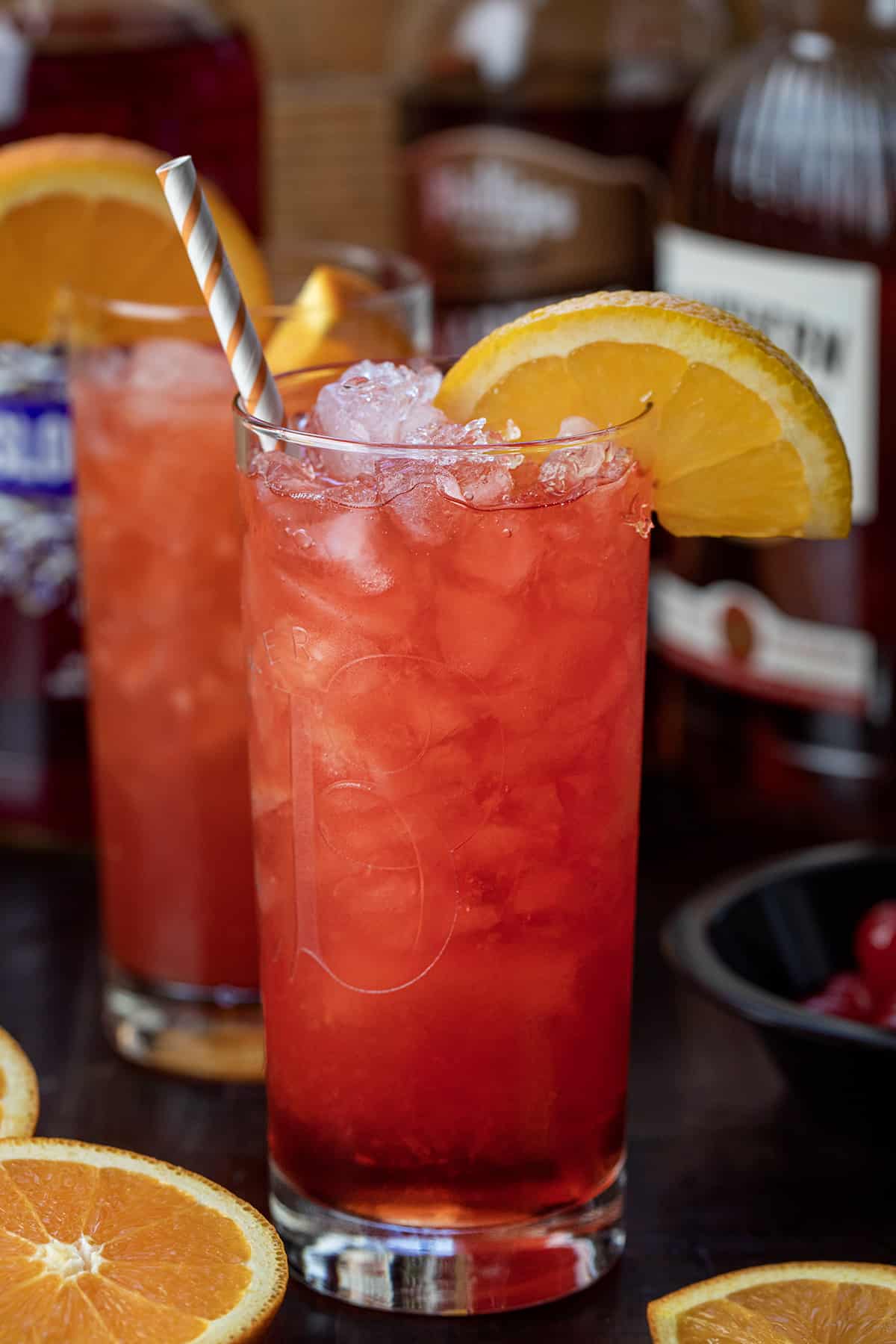 Alabama Slammer Cocktail on a Cutting Board with Oranges and a Straw. 