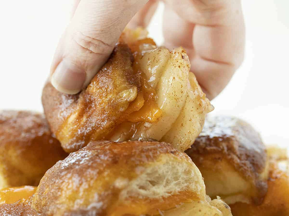 Hand Picking Up Apple Cheddar Sliders From a Stack