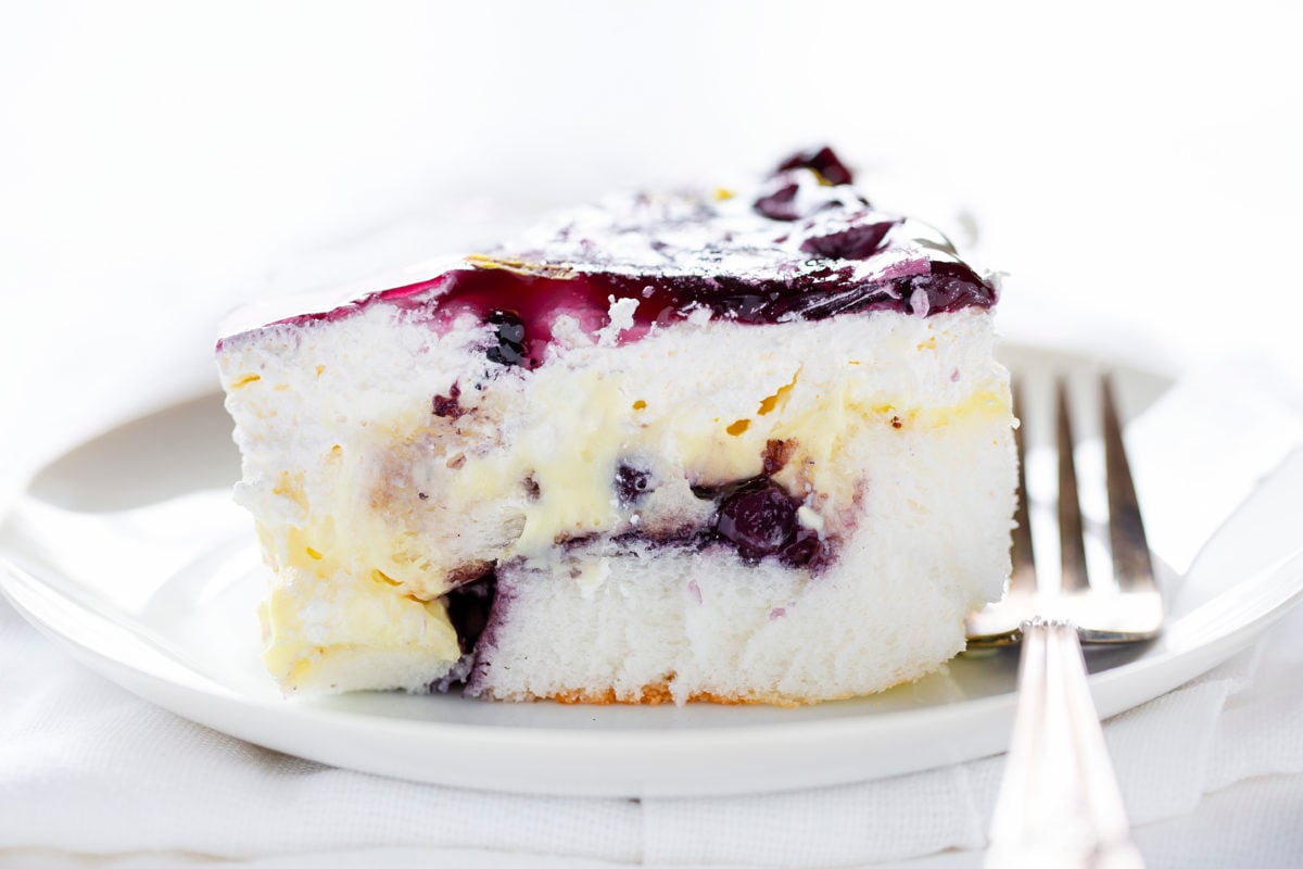 Blueberry Lemon Heaven Dessert On a Plate Showing Layers of Angel Food Cake, Blueberry Pie Filling, and Lemon Pudding.
