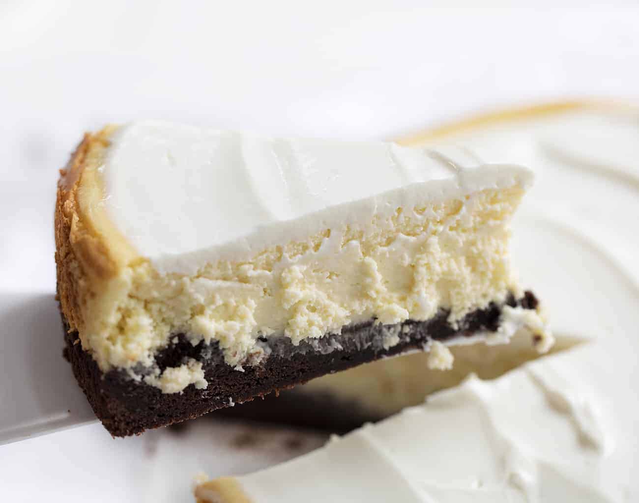 Removing Piece of Brownie Bottom Cheesecake from Platter and Holding Up