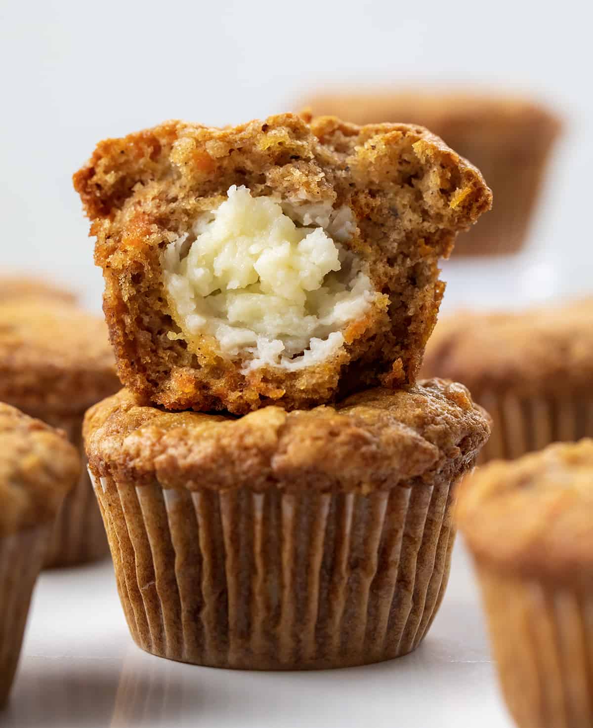 Cream Cheese Filled Carrot Cake Cupcakes Stacked and Surrounded by More Cupcakes.