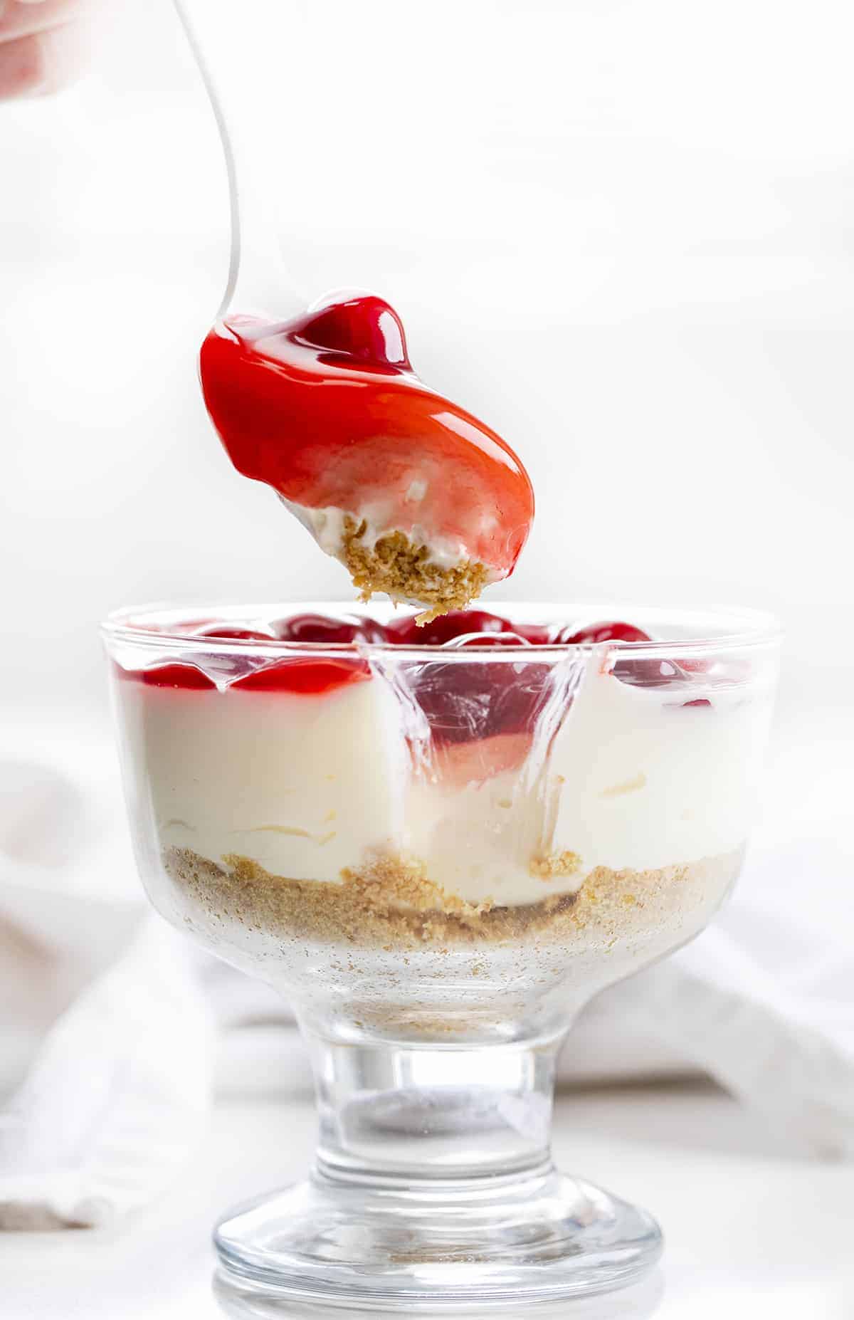 Spoon Taking a Bite out of No-Bake Cherry Cheesecake Parfait.