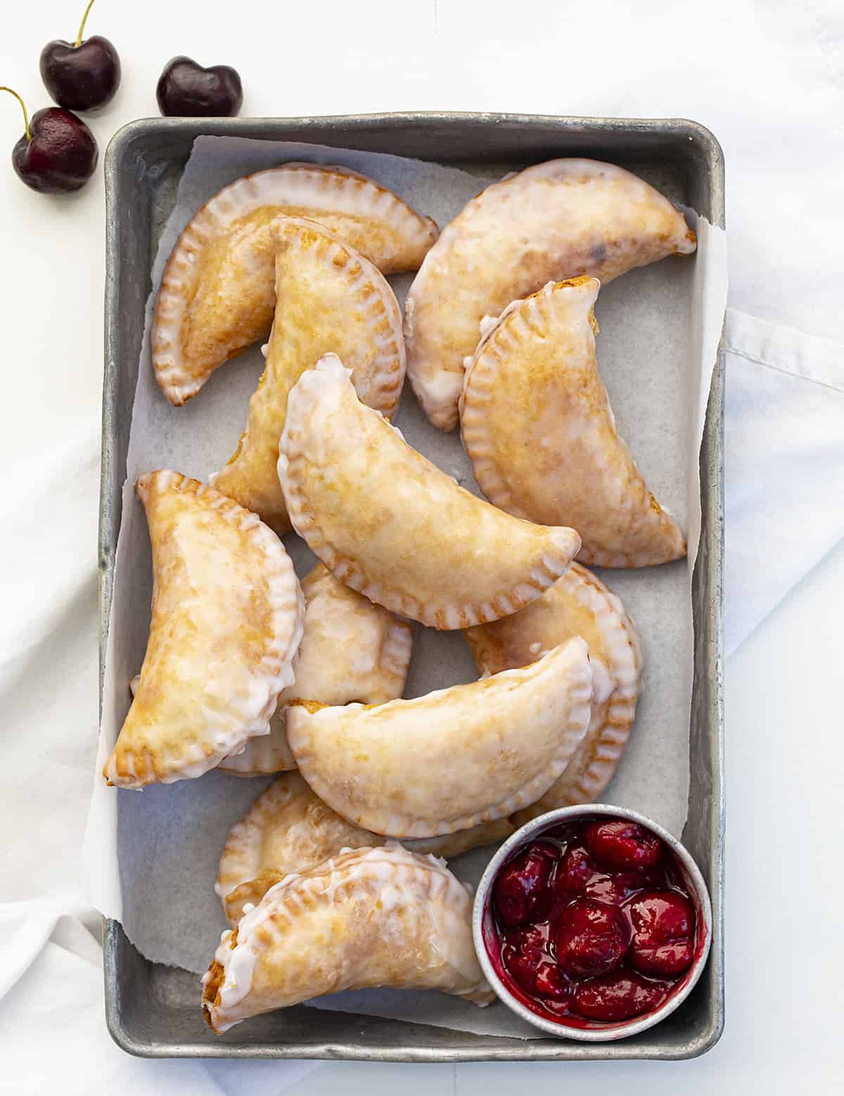 Pan of Cherry Hand Pies from OVerhead. Dessert, Snack, Hand Pies, Fried Pies, Fried Hand Pies, Cherry Pies, Air Fryer Cherry Hand Pies, Fried Cherry Hand Pies, Oven Cherry Hand Pies, Cherry Desserts, Baking, Cherry Recipes, Christmas Recipes, Summer Desserts, i am baker, iambaker