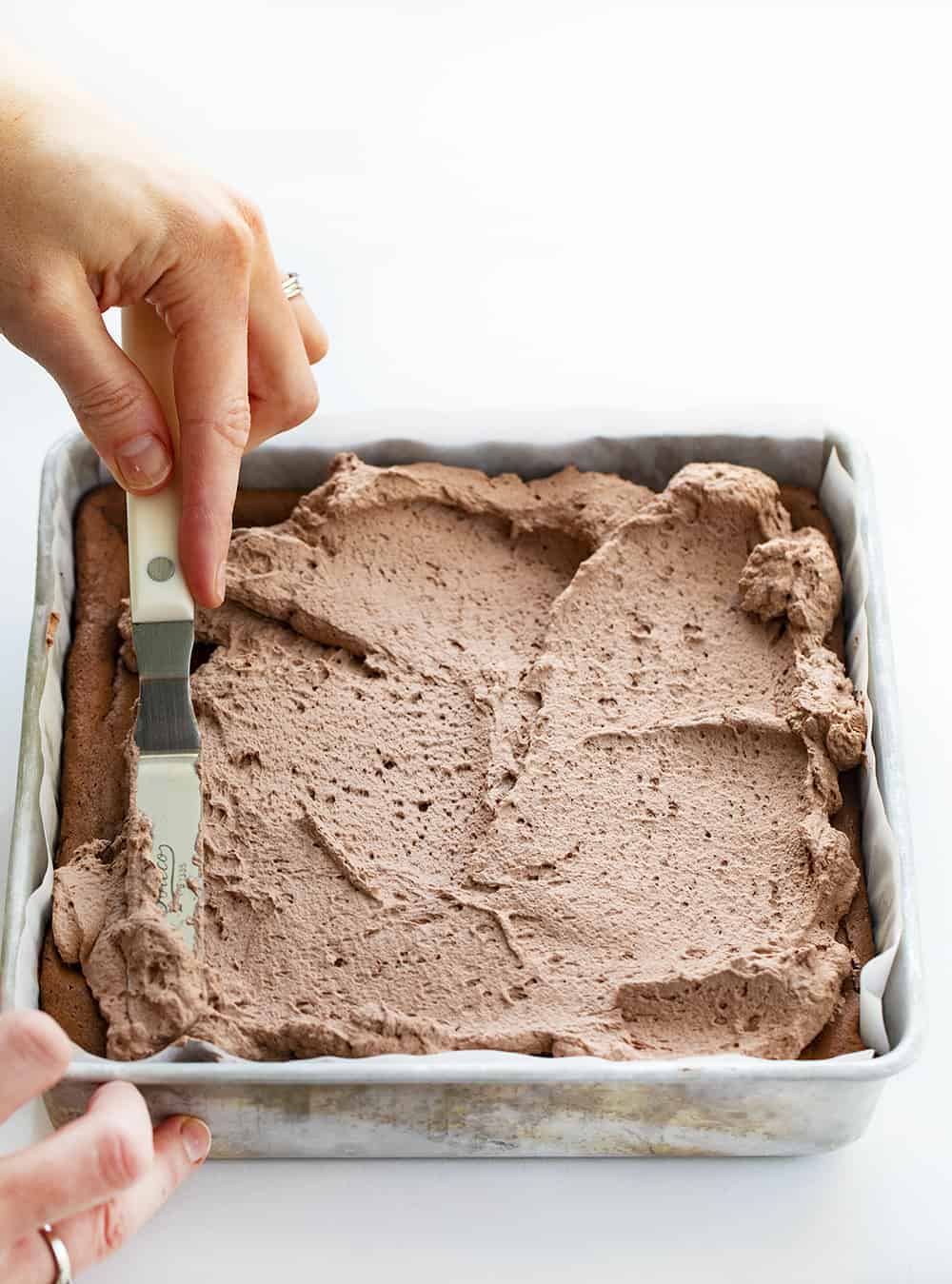 Spreading Chocolate Whipped Topping over Chocolate Cheesecake Bars