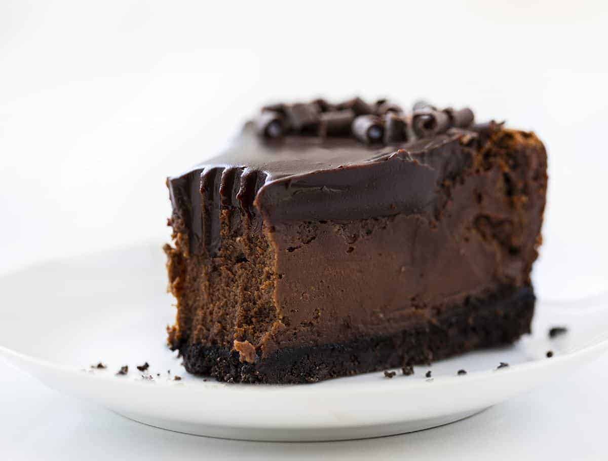 Piece of Chocolate Cheesecake with Bite Removed from the Tip on a White Plate