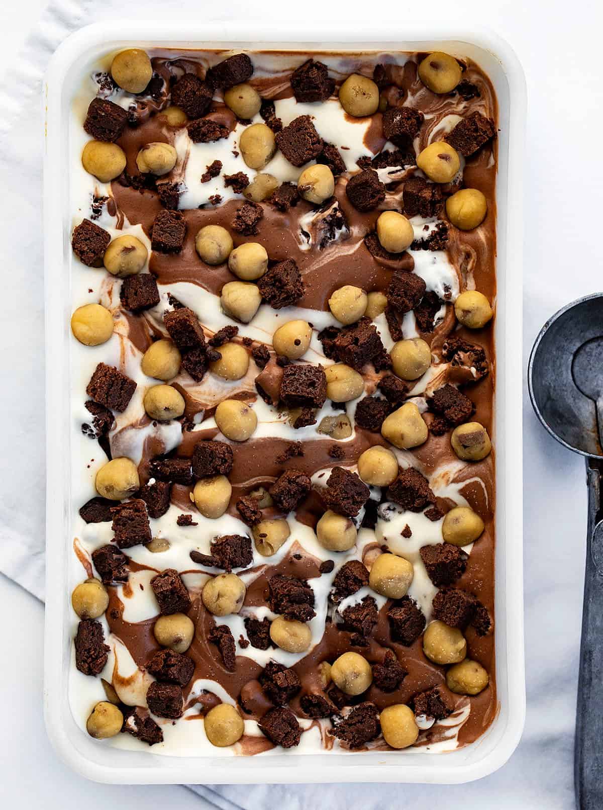 Pan of Cookie Dough Brownie Ice Cream from OVerhead with Ice Cream Scoop Next to It.