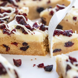 Fork Taking a Bite out of Cranberry Bliss Bar Showing the Soft Texture of the Bar and Creamy Cream Cheese Frosting.