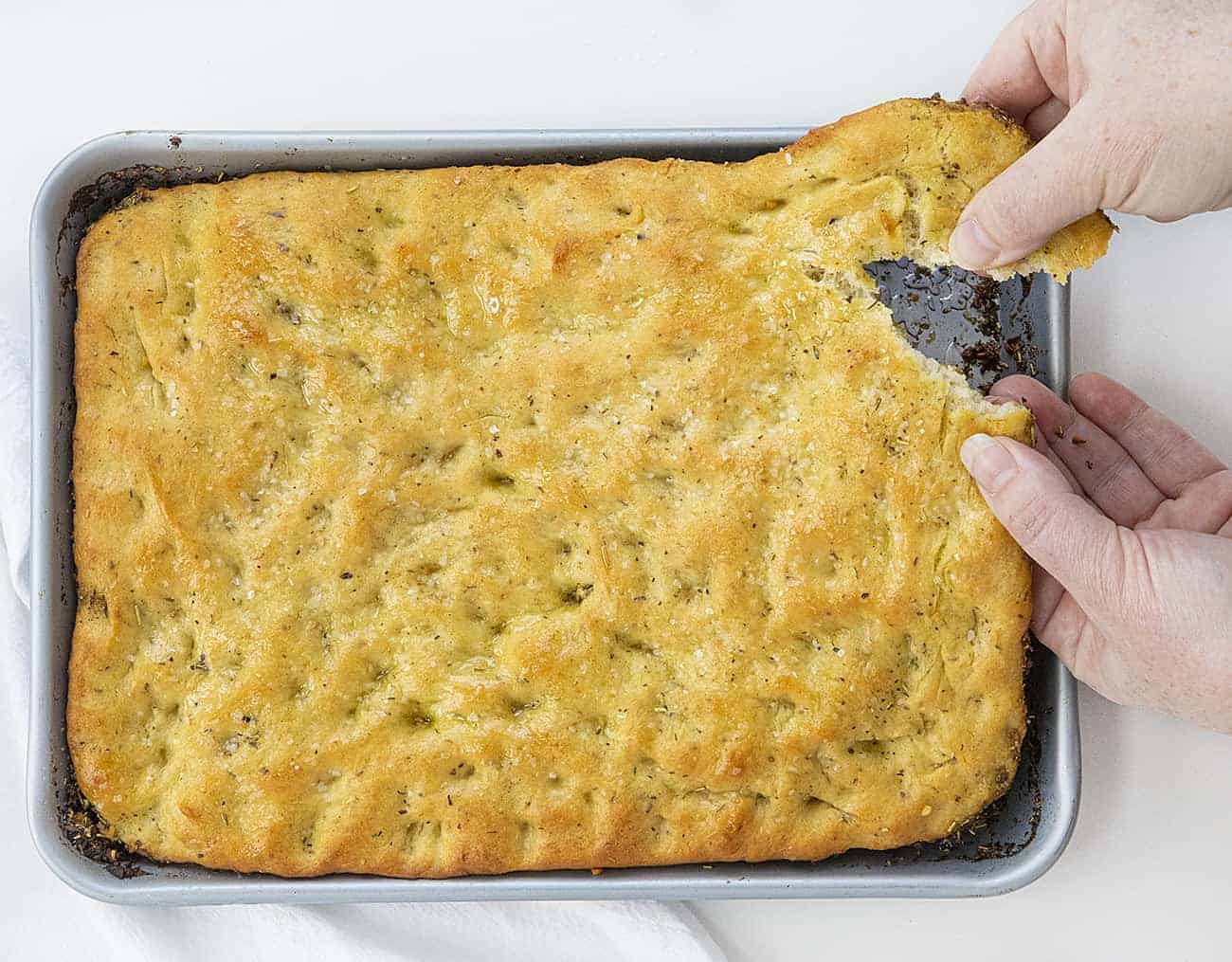 Hands Tearing off a Piece of Focaccia Bread