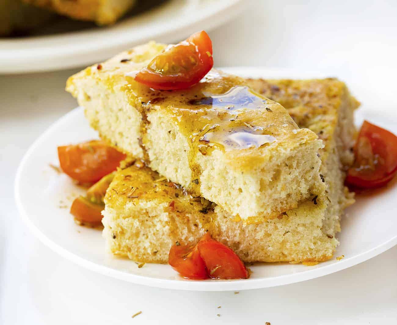 Focaccia Bread that has been Drizzled with Oil and Balsamic Vinegar on a White Plate with Tomato