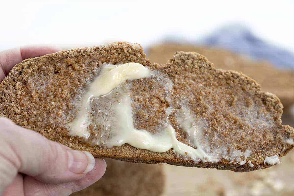 Hand Holding Piece of Irish Soda Bread with Butter Melting on It