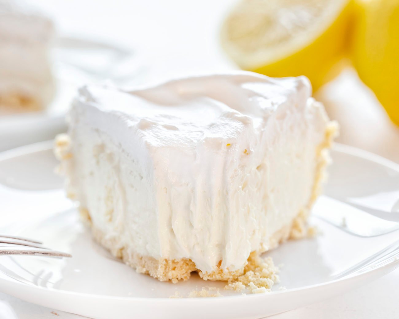 Lemon Mousse Pie on a Plate with a Bite Removed with a Fork.
