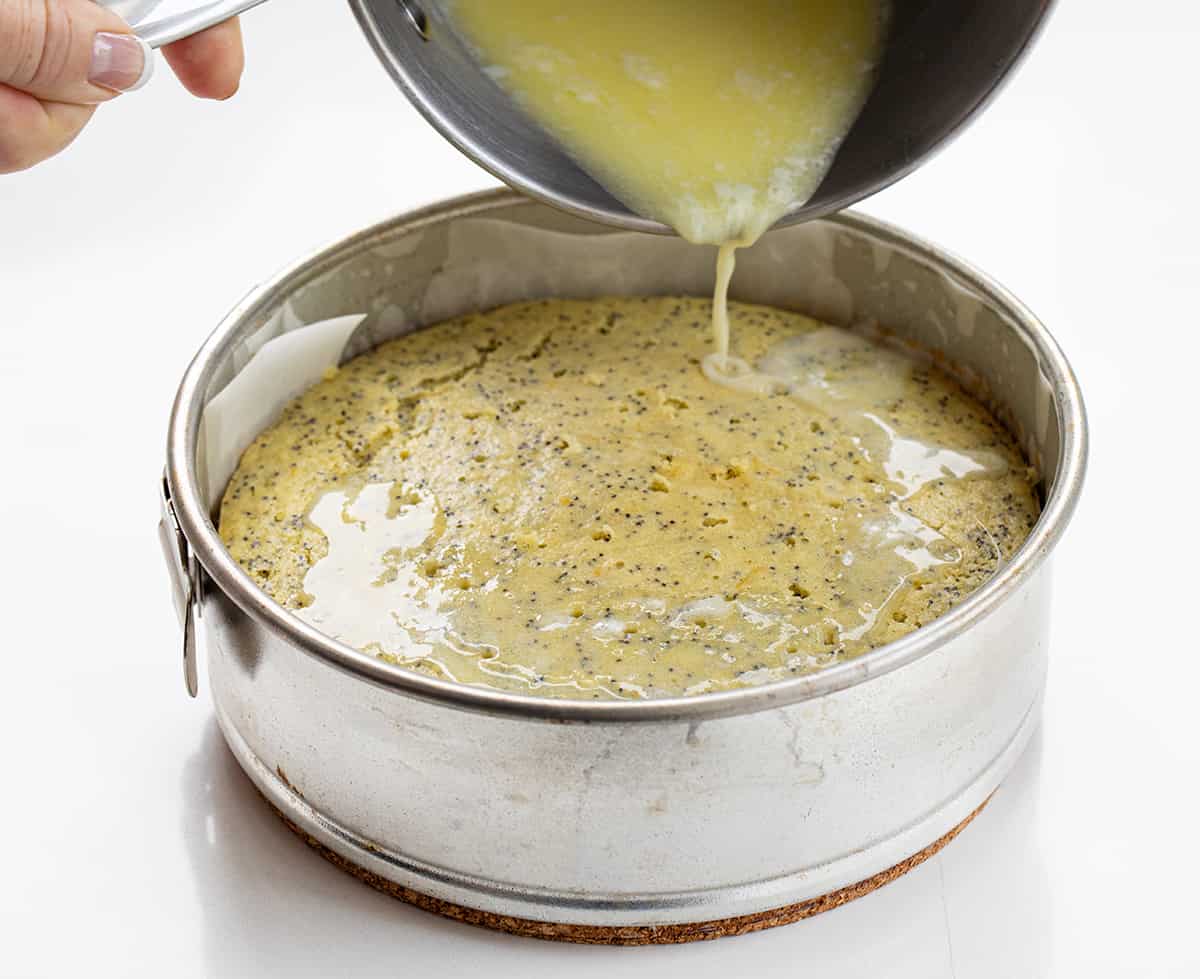 Pouring Milk Mixture Over Hot Lemon Poppyseed Cake That is Still In the Springform Pan.