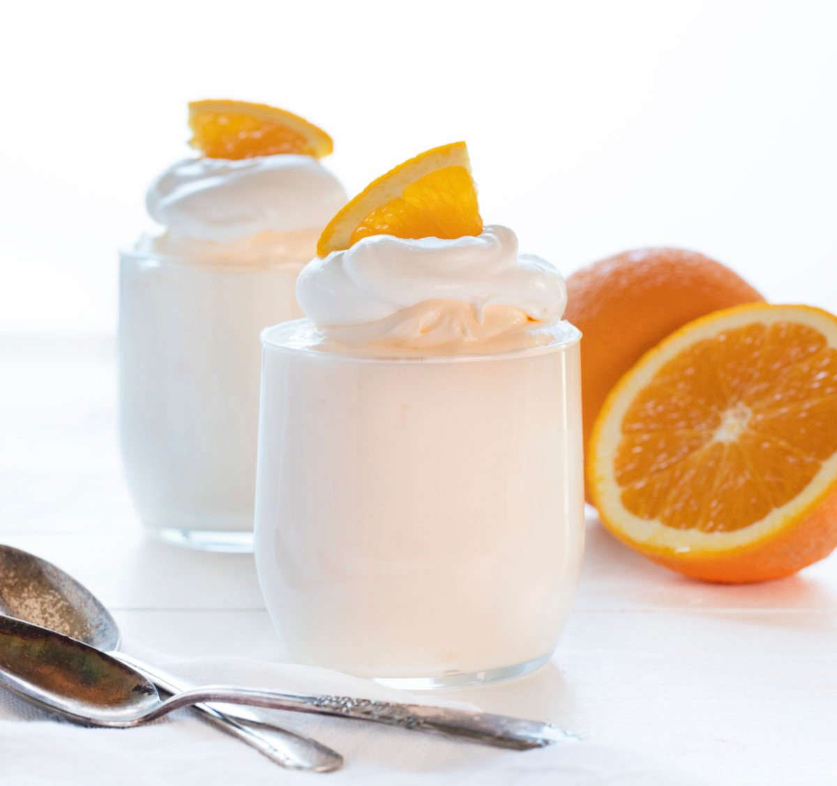 Orange Creamsicle Mousse in Glasses with Oranges in Background and Spoons in Front.