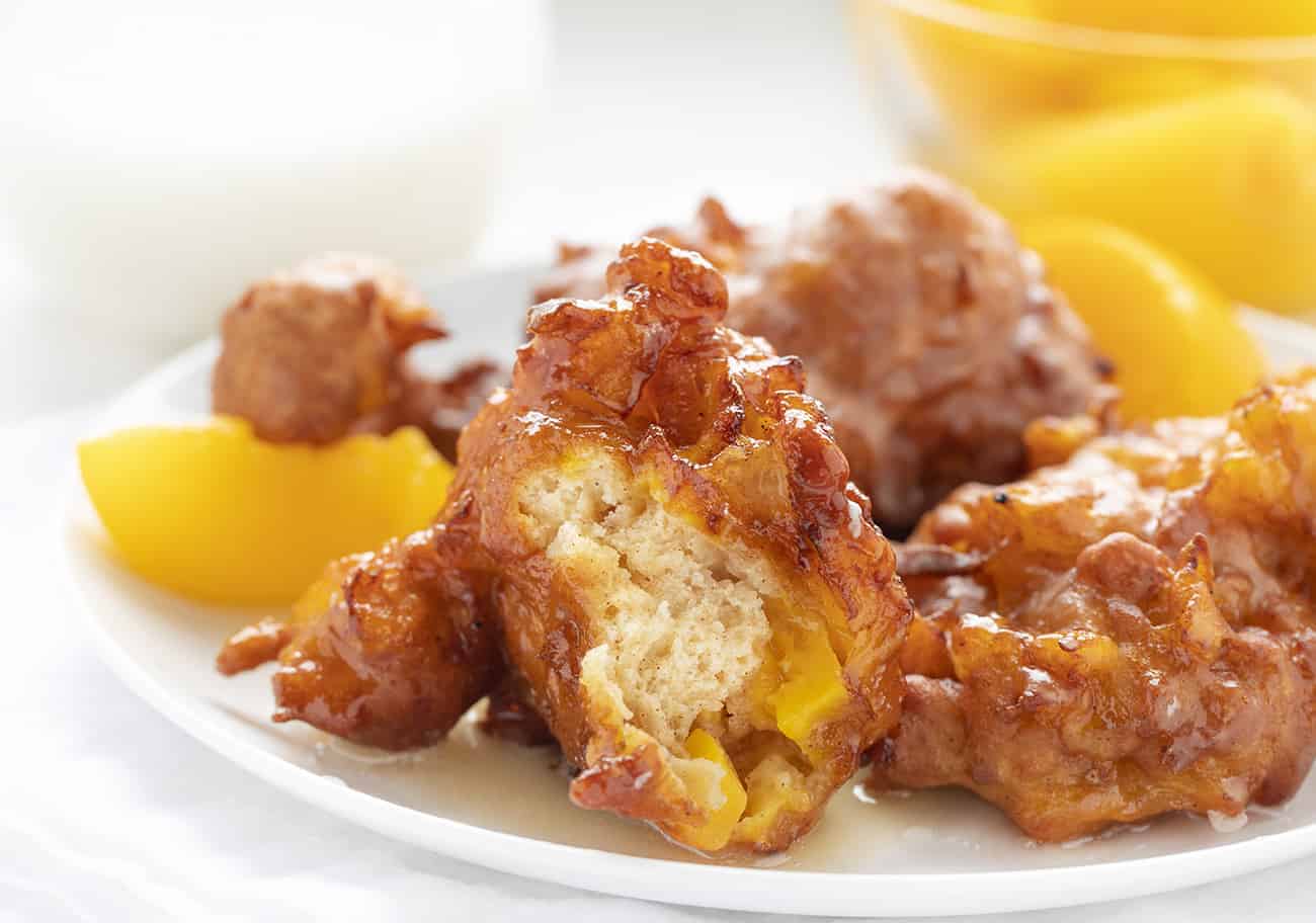 Peach Fritters on a White Plate, one of them bit into