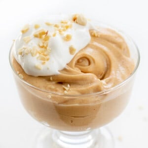 COntainer of Peanut Butter Mousse with Whipped Topping and Peanuts Chopped on Top.