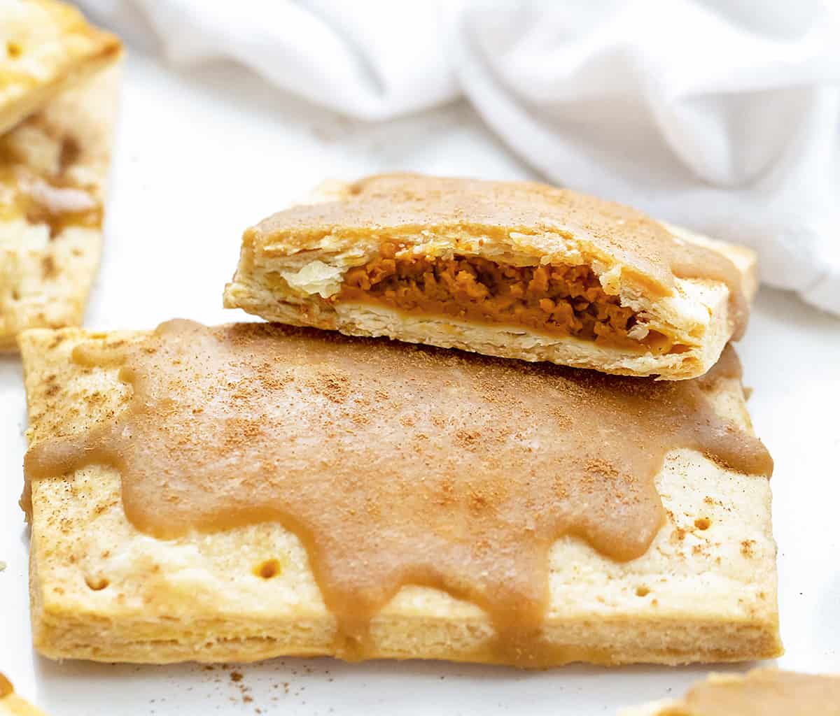 One Whole and One Halved Pumpkin Pie Pop Tart on White Counter. Breakfast, Pumpkin Dessert, Pumpkin Recipes, Baking, How to Make Pop Tarts, Breakfast Recipe Ideas, Dessert, Snacks, Treats, Fall Treats, Fall Baking Recipes, i am baker, iambaker