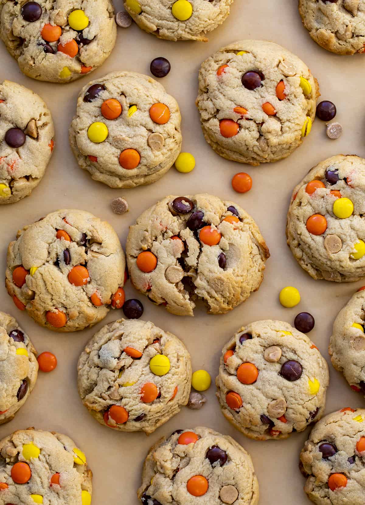 Reese's Pieces Peanut Butter Cookies on Parchment from Overhead with Middle Cookie Broken in Half.