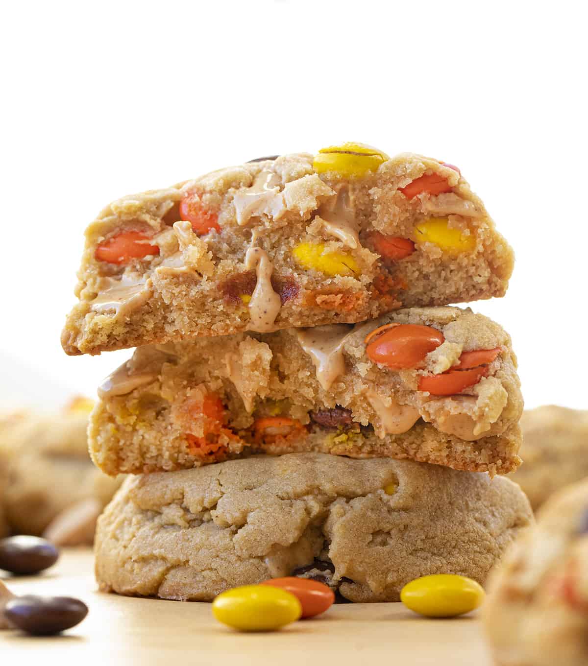 Stacked Reese's Pieces Peanut Butter Cookies and Top Cookie Broken in Half Showing Inside.
