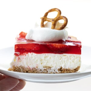 Hand Holding a Plate of Strawberry Pretzel Salad.