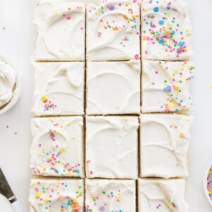 Whole Vanilla-Delight Cake or White Cake on a White Counter with Pastel Sprinkles and Cut Into Pieces.