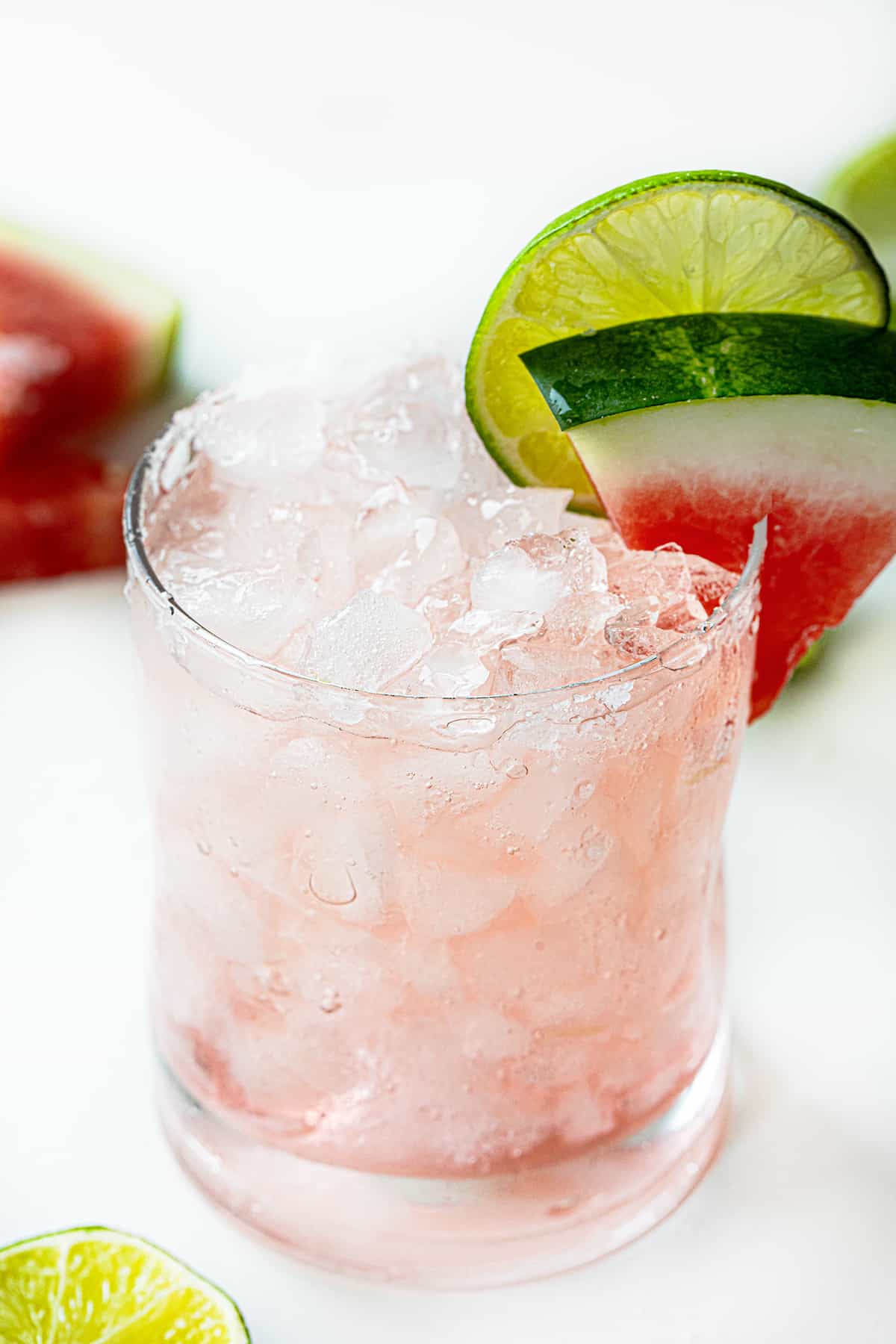 Glass Filled with a Watermelon Refresher Cocktail with a Watermelon Wedge and Lime.